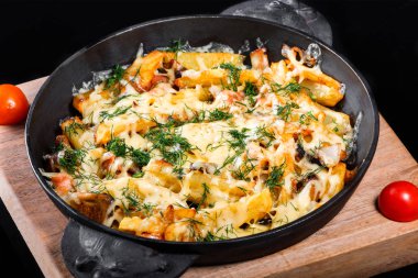 Tavada domates, otlar ve siyah arka plan üzerinde ev yapımı yiyecek izole ahşap tahta üzerinde peynir ile kızarmış veya fırında patates