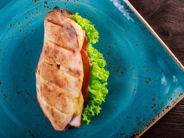 Marul ile taze Pide, dilim taze domates, jambon domuz eti ve koyu ahşap zemin üzerine peynir sandviç. Sağlıklı öğle yemeği. Üstten görünüm, düz lay