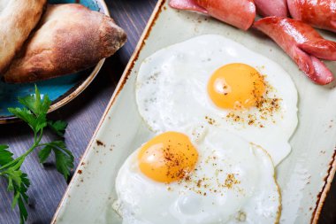 Kızarmış yumurta ve sosis ekmek ve taze sebze ile. Sıcak ve sağlıklı kahvaltı, üstten görünüm, düz yatıyordu