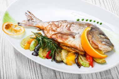 Izgara dorado balık pişmiş sebze ve biberiye plaka ahşap zemin üzerine kapatın. Sağlıklı gıda. Üstten görünüm