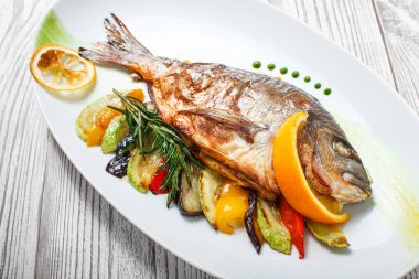 Izgara dorado balık pişmiş sebze ve biberiye plaka ahşap zemin üzerine kapatın. Sağlıklı gıda. Üstten görünüm