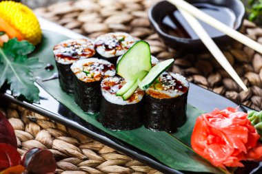 Suşi Roll - Maki Sushi füme yılan balığı, salatalık, avokado ve susam çiçeklerle süslenmiş bambu mat siyah taş. Japon mutfağı