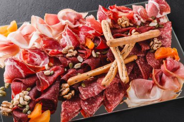 Meze tabağı soğuk et grisini ekmek ile sopa, jambon, dilim jambon, sığır eti, salam, et ve siyah taş zemin üzerine fındık. Et iştah açıcı, gıda kavramı karşılayan