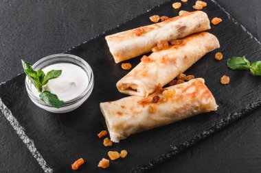 Tofu peyniri, pesto sos ve plaka üzerinde roka ile doldurulmuş krep. Bir koyu gri taş yüzeye görüntüleyin. Sağlıklı kahvaltı