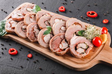 Çeşitli et, tavuk dolması rulo, et rulo ile biber, yeşillik siyah şeyl arka plan üzerinde kesme tahtası üzerinde. Et iştah açıcı, gıda kavramı. Üstten görünüm, düz yatıyordu