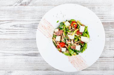Taze sebze salatası jambon, ıspanak, mantar, domates, peynir, soğan, salatalık ve hafif ahşap arka plan üzerinde plaka üzerinde avokado ile. Sağlıklı gıda. Üstten görünüm