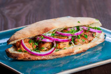 Izgara tavuk sandviç soğan ve koyu ahşap arka plan üzerinde yeşillik ile taze Pide üzerinden. Şaşlık veya şiş kebap. Sağlıklı yemek