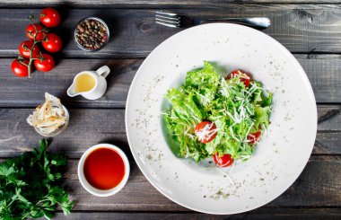 Karışık yeşillik, domates, ahşap zemin üzerine parmesan peyniri ile taze salata. Sağlıklı gıda. Maddeler tablosundaki