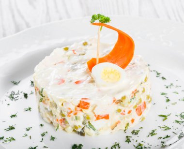 Geleneksel Rus Noel ve yılbaşı salatası Olivier plaka üzerinde ışık dekorasyon ahşap. Üstten görünüm