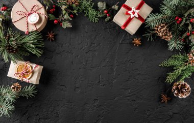 Yaratıcı düzen çerçeve yaptı Noel ağaç dalları, çam kozalakları, koyu arka plan üzerinde hediyeler. Noel ve yeni yıl tema, kar. Düz yatıyordu, en iyi görünüm, geniş kompozisyon