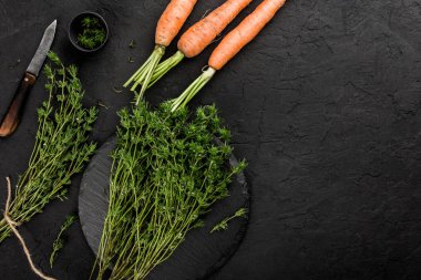 Sağlıklı ham yaz vegan sebzeler, havuç ve bitki kekik karanlık taş zemin üzerine. Sağlıklı gıda, yemek, temiz yemek, üstten görünüm, düz yatıyordu, kopya alanı