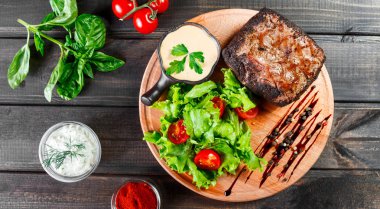 Izgara biftek domuz eti taze sebze salatası, domates ve ahşap kesme tahtası üzerinde sos ile