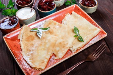 Krepler ekşi krema, pudra şekeri, meyve reçel, marmelat ve meyveleri koyu ahşap zemin üzerinde. Hafta ya da Shrovetide krep geleneksel Rus mutfağı. Düz yatıyordu. Üstten görünüm