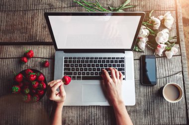 Çalışma alanı kız eli, dizüstü bilgisayar, şakayık çiçeği buketi, kahve, çilek, ahşap masada akıllı telefon. Açık hava parkında çalışan serbest çalışan biri. Üst kat ofis masası. Düz yatıyordu