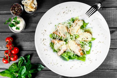 Tavuk göğsü, parmesan peyniri, kruton, karışık yeşillik, ahşap arka plan üzerinde marul salatası. Sağlıklı gıda. Maddeler tablosundaki