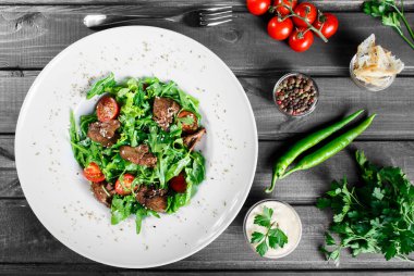 Sıcak kızarmış karaciğer, kiraz domates ve koyu ahşap zemin üzerine karışık yeşillik salatası. Sağlıklı gıda. Maddeler tablosundaki. Üstten görünüm