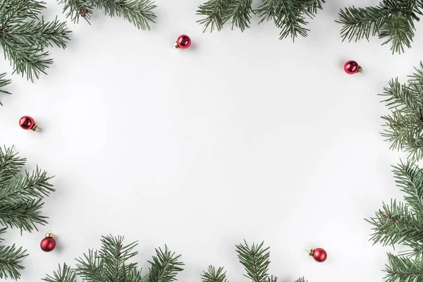 Yaratıcı çerçeve Noel köknar yapılan dalları kırmızı dekorasyonu, çam kozalakları ile beyaz arka plan üzerinde. Noel ve yeni yıl tema. Düz yatıyordu, en iyi görünümü