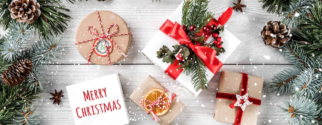 Christmas gift boxes on white wooden background with Fir branches, pine cones. Xmas and Happy New Year theme, snowflakes. Flat lay, top view