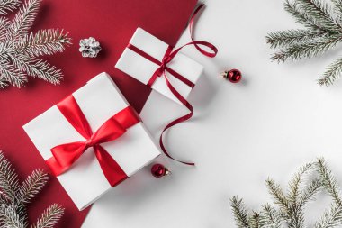 Noel hediye kutuları kırmızı kurdele, dekorasyon, çam dalları, çam kozalakları beyaz ve kırmızı Kağıt arka plan ile. Noel ve mutlu yeni yıl tema. Düz yatıyordu, en iyi görünüm, metin için yer