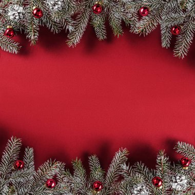 Yaratıcı düzen çerçevesi Noel köknar yapılan dalları, çam kozalakları, kırmızı Kağıt arka plan üzerinde kırmızı dekorasyon. Noel ve yeni yıl tema. Düz yatıyordu, en iyi görünümü