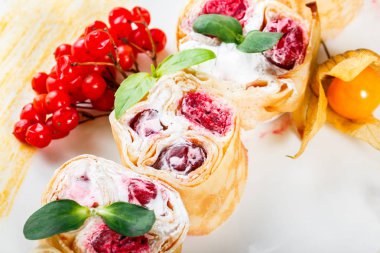 Krem peynirli gözleme, kiraz çilek ve hafif ahşap zemin üzerine physalis tarafından dekore edilmiş kapatmak. Geleneksel Rus yemekleri. Şekerli tatlı. Düz yatıyordu. Üstten görünüm