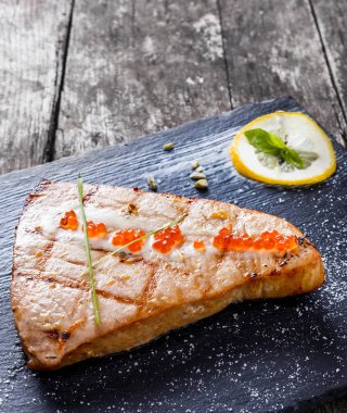 Kırmızı havyar ve kayrak taş zemin üzerine limon ile pişmiş somon fileto kapatın. Sağlıklı gıda