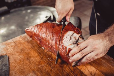 Şef ızgara kesme elinde bıçakla kesme tahtası üzerinde domuz biftek için ızgara. Sıcak et yemekleri