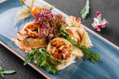 Tofu peyniri, pesto sos ve plaka üzerinde roka ile doldurulmuş krep. Bir koyu gri taş yüzeye görüntüleyin. Sağlıklı kahvaltı