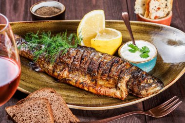 Limon ve Yeşiller ahşap arka plan üzerinde plaka üzerinde pişmiş balık. Lezzetli yemek deniz ürünleri