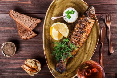 Limon ve Yeşiller ahşap arka plan üzerinde plaka üzerinde pişmiş balık. Lezzetli yemek deniz ürünleri. Üstten görünüm