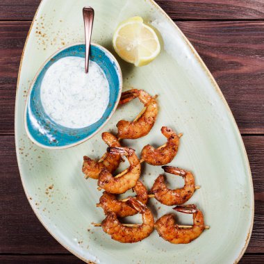 Kızarmış karides şiş sos ve ahşap masa üzerinde plaka üzerinde limon ile üzerinde. Lezzetli yemek deniz ürünleri. Üstten görünüm