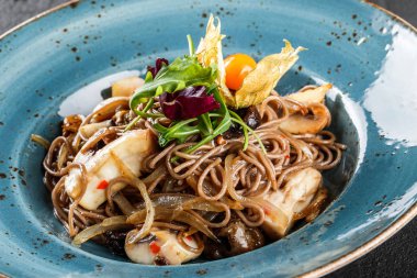 Tatlı ve ekşi sos, soğan ve plaka karanlık taş zemin üzerine yeşil yabani mantar ile soba erişte. Üstten görünüm