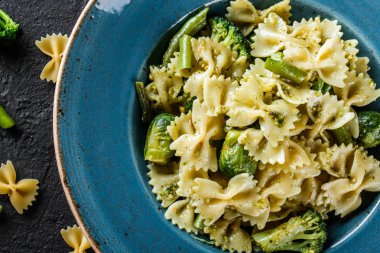 Vegan Farfalle makarna ıspanak soslu brokoli, Brüksel lahanası, plaka karanlık taş zemin üzerine yeşil fasulye ile. Üstten görünüm, düz yatıyordu. Vejetaryen yiyecekler