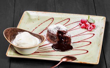 Çikolatalı kek veya fondan ahududu ve koyu ahşap arka plan, tatlı gıda topa vanilyalı dondurma ile