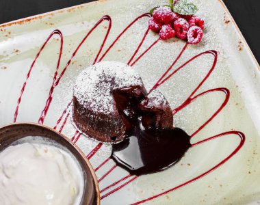 Çikolatalı kek veya fondan ahududu ve koyu ahşap arka plan, tatlı gıda topa vanilyalı dondurma ile