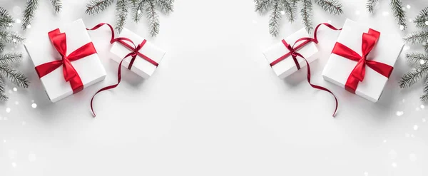 Yaratıcı çerçeve Noel köknar yapılan Beyaz Kağıt arka plan kırmızı süslemeli, çam kozalakları dallarda. Noel ve yeni yıl tema, kar taneleri, bokeh. Düz yatıyordu, en iyi görünümü