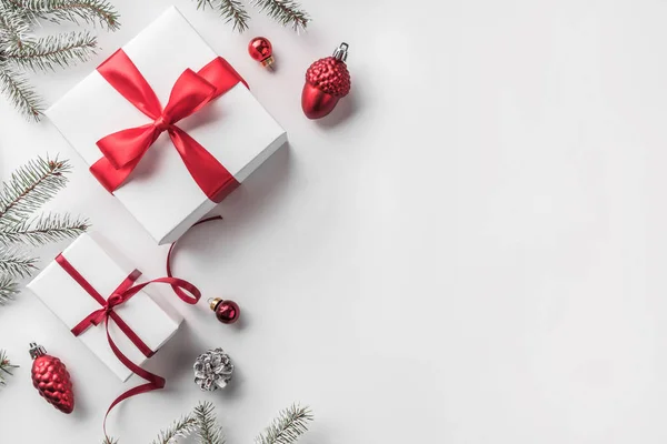 Рождественские Подарочные Коробки Белом Фоне Еловыми Ветвями Сосновыми Шишками Красным — стоковое фото