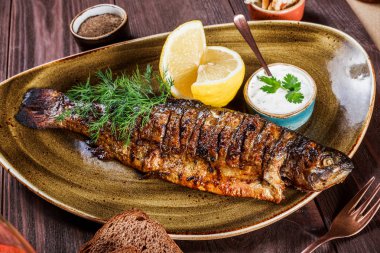 Limon ve Yeşiller ahşap arka plan üzerinde plaka üzerinde pişmiş balık. Lezzetli yemek deniz ürünleri