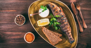 Limon ve Yeşiller ahşap arka plan üzerinde plaka üzerinde pişmiş balık. Lezzetli yemek deniz ürünleri. «Ana sayfa» görünümü, tonlama