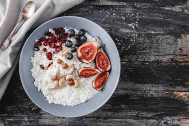 Pilav Hindistan cevizi yulaf lapası incir, çilek, fındık, Kuru kayısı ve plaka rustik ahşap zemin üzerine Hindistan cevizi sütü ile. Sağlıklı kahvaltı malzemeler. Yeme, vegan gıda kavramı temiz. Üstten görünüm