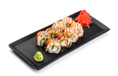 Suşi Roll - Maki Sushi somon yapılmış, yılan balığı, salatalık, avokado ve krem peynir beyaz arka plan üzerinde izole siyah plaka üzerinde füme. Japon mutfağı