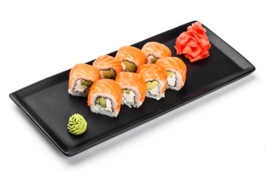 Suşi Roll - somon, avokado ve krem peynir beyaz arka plan üzerinde izole siyah plaka üzerinde Maki Sushi yapılmış. Japon mutfağı