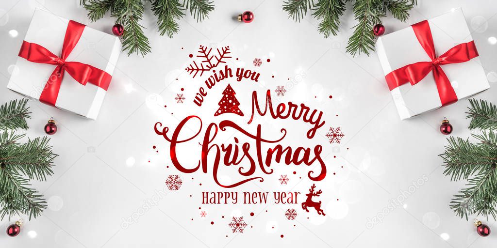 Merry Christmas Typographical on white background with gift boxes, fir branches, red decoration. Xmas and New Year card, bokeh, light. Flat lay, top view