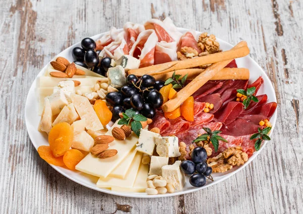 Antipasto platter cold meat with grissini bread sticks, prosciutto, slices ham, beef jerky, salami and cheese platter on rustic background. Appetizer, catering food concept