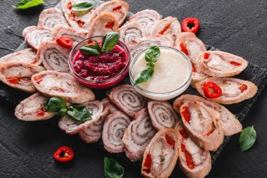 Çeşitli et, tavuk dolması rulo, et rulo ile biber, yeşillik siyah şeyl arka plan üzerinde. Et iştah açıcı, gıda kavramı. Üstten görünüm, düz yatıyordu