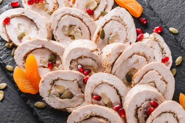 Çeşitli et, tavuk dolması rulo, et rulo Narlı, Yeşiller siyah şeyl arka plan üzerinde. Et iştah açıcı, gıda kavramı. Üstten görünüm, düz yatıyordu