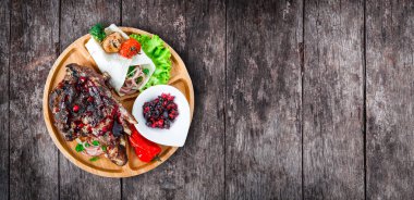 Kemik berry soslu ızgara antrikot biftek, taze salata ve ızgara sebze kesme tahtası ahşap zemin üzerine kapatın. Sıcak et yemekleri. Üstten görünüm