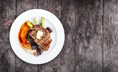 Tatlım, biberiye, kuşkonmaz ve pancar salatası ahşap arka plan üzerinde tarihleri ızgara domuz eti biftek. Sıcak et yemekleri. Üstten görünüm, düz yatıyordu