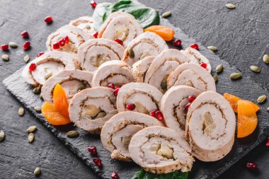 Çeşitli et, tavuk dolması rulo, et rulo Narlı, Yeşiller siyah şeyl arka plan üzerinde. Et iştah açıcı, gıda kavramı. Üstten görünüm, düz yatıyordu