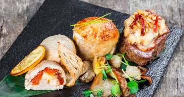 Sığır eti biftek ve prosciutto ve ahşap arka plan üzerinde taş arduvaz arka plan üzerinde peynir ile tavuk göğsü. Sıcak et yemekleri. Üstten görünüm 